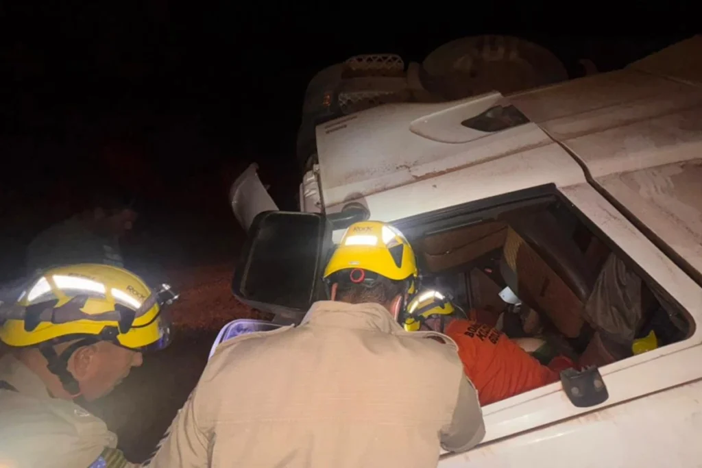 Carreta com soja tomba e motorista fica presa às ferragens